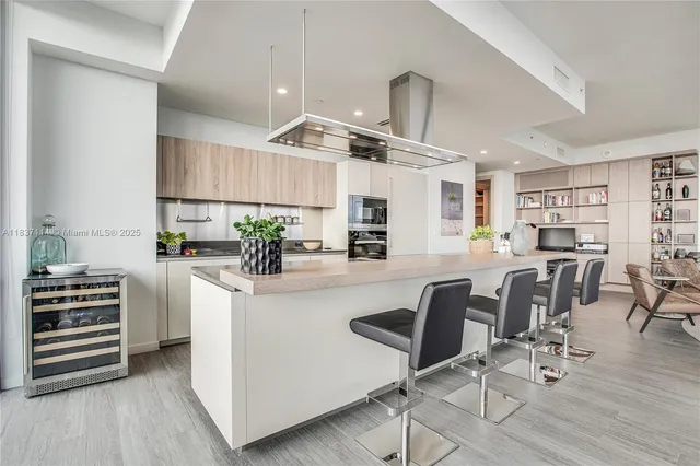 a kitchen with stainless steel appliances kitchen island granite countertop a table chairs and a refrigerator