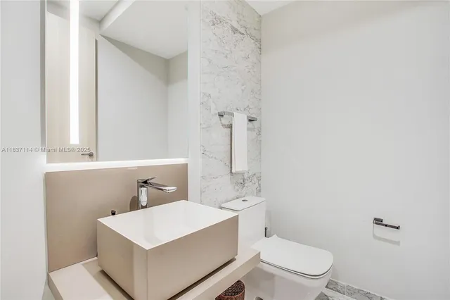 a white toilet sitting next to a bathroom sink