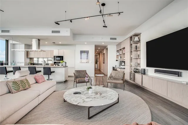 a living room with furniture kitchen view and a flat screen tv