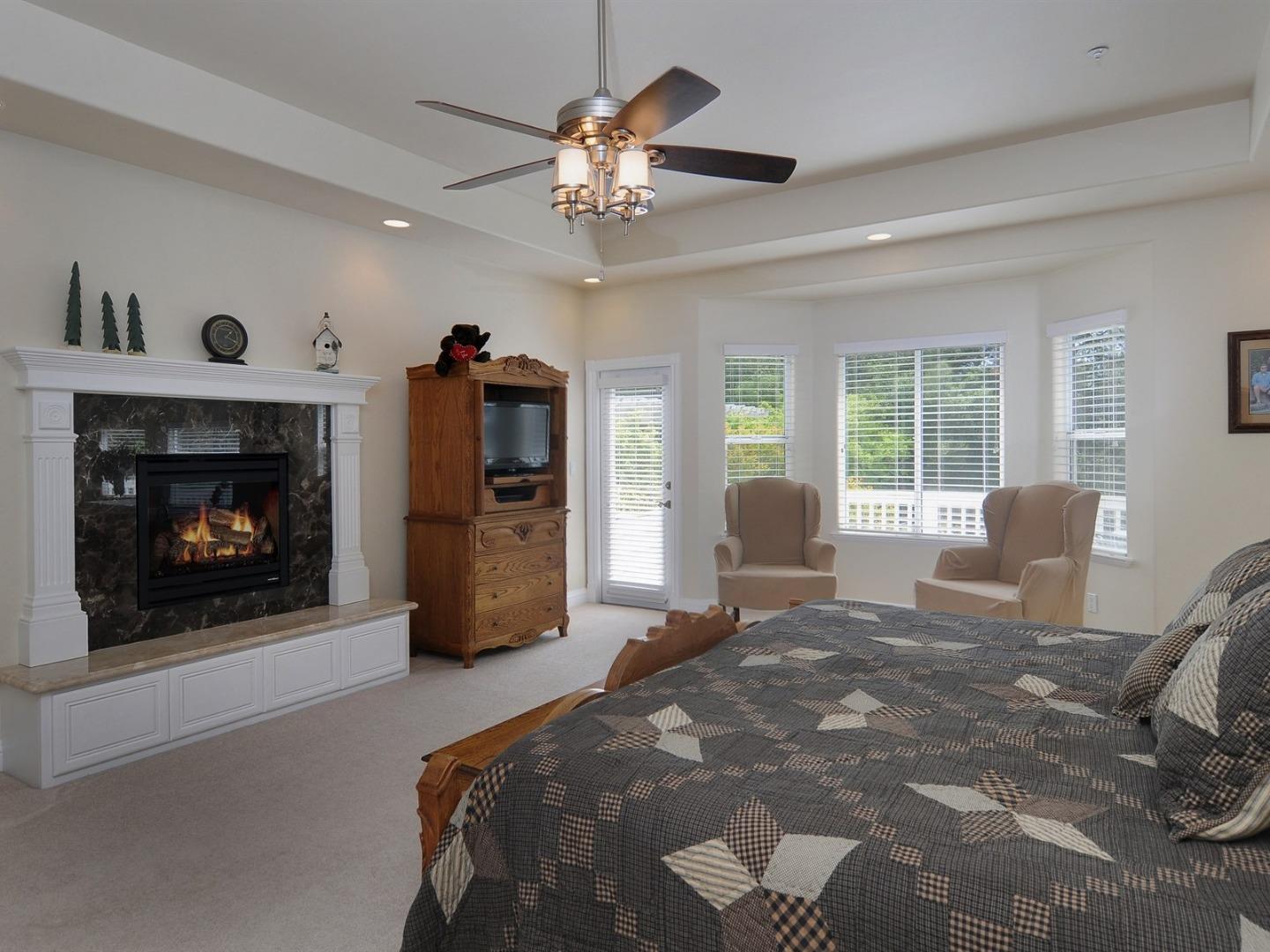 10035 Burchell Road Gilroy, CA 95020 - Photo 20 of 55 a bedroom with a bed a fireplace and a chandelier