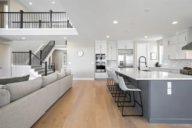a living room with stainless steel appliances kitchen island granite countertop a stove a sink a refrigerator and white cabinets