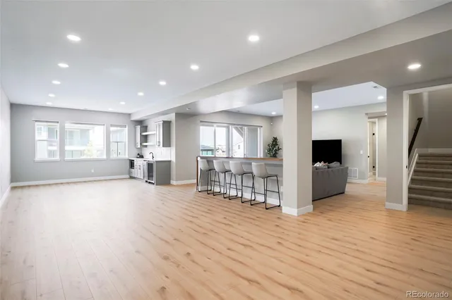a view of an empty room with wooden floor and a kitchen