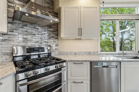 a kitchen with granite countertop a sink stainless steel appliances and a window