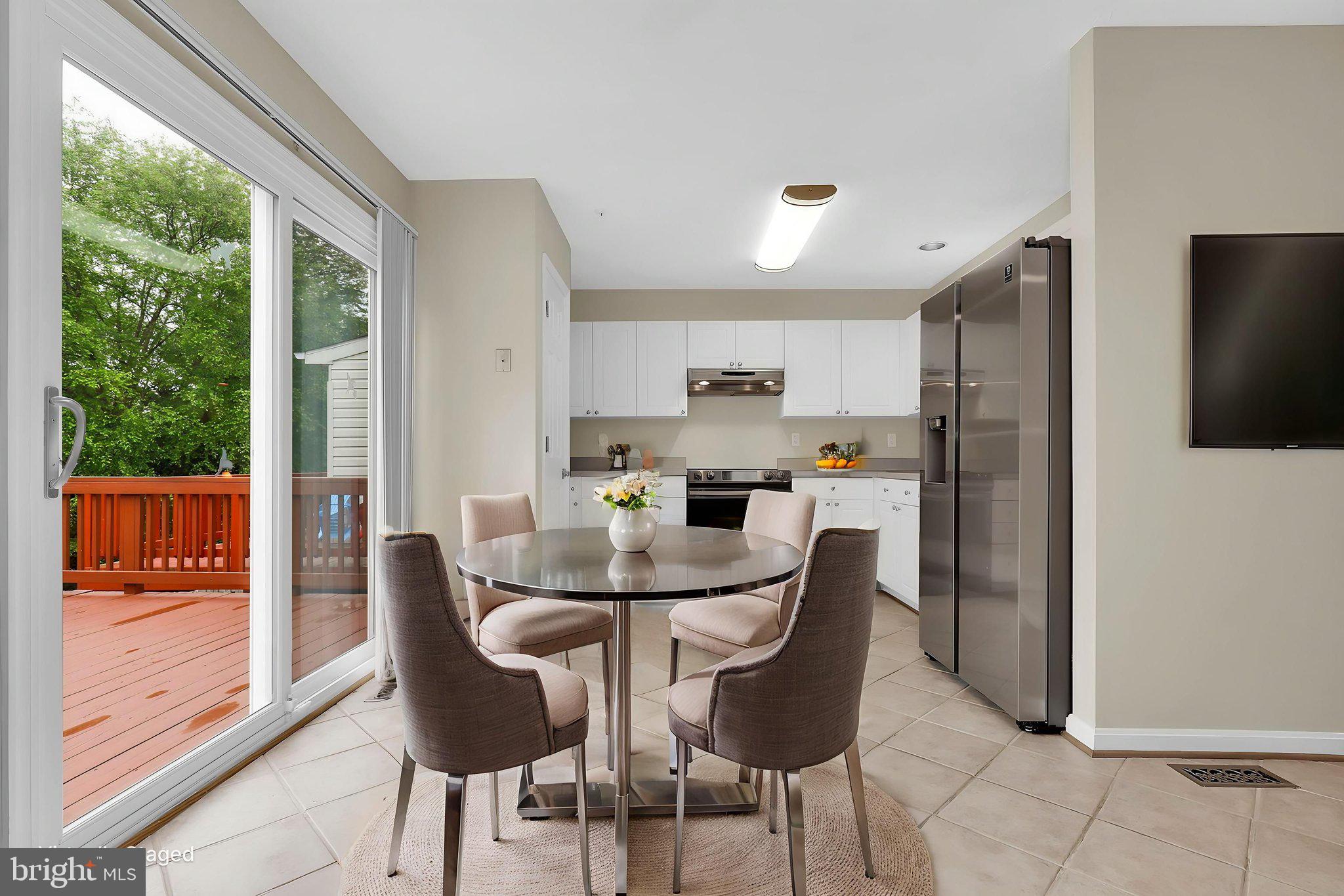 7150 Natures Road Columbia, MD 21046 - Photo 10 of 45 a kitchen with stainless steel appliances granite countertop a refrigerator a microwave oven a dining table and chairs with wooden floor