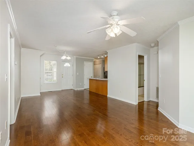 a view of an empty room with wooden floor and a window