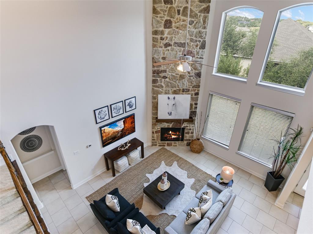 2657 Montebelluna Place Leander, TX 78641 - Photo 12 of 29 Tiled living room with ceiling fan, a high ceiling, and a fireplace