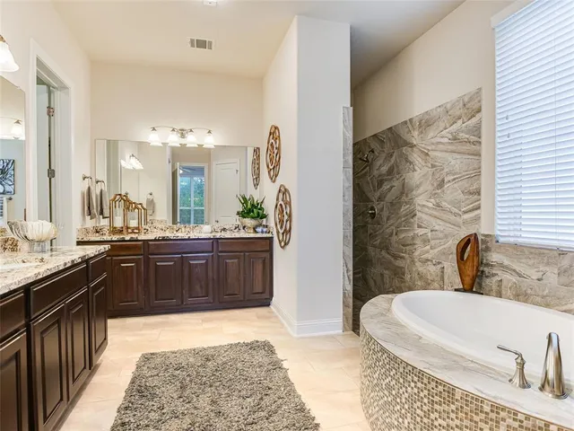 a bathroom with a granite countertop sink and a bathtub