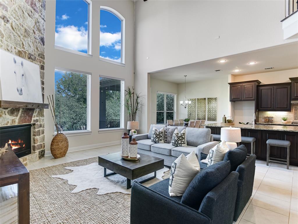 2657 Montebelluna Place Leander, TX 78641 - Photo 5 of 29 Living room with light tile patterned flooring, a chandelier, a fireplace, and a high ceiling