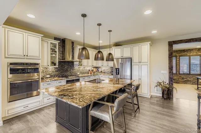 a kitchen with granite countertop a stove a sink a dining table and chairs