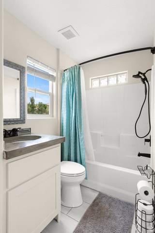 2591 East Washington Dam Road Washington, UT 84780 - Photo 36 of 67 Bathroom featuring a modern vanity with a dark countertop and vessel sink, white cabinetry, a large window, a tub/shower combination with black fixtures, and light-toned tile flooring