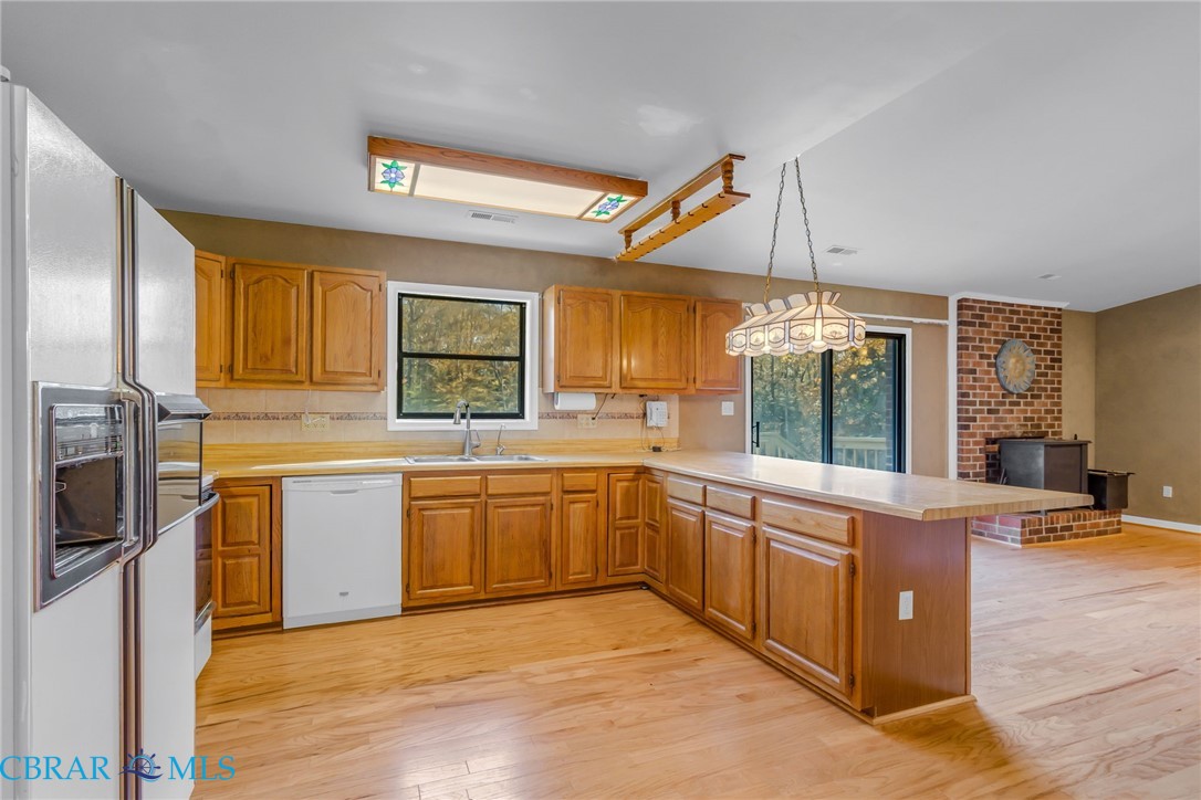 278 Regent Road Hartfield, VA 23071 - Photo 9 of 49 Kitchen featuring white appliances, light countertops, brown cabinets, and a peninsula