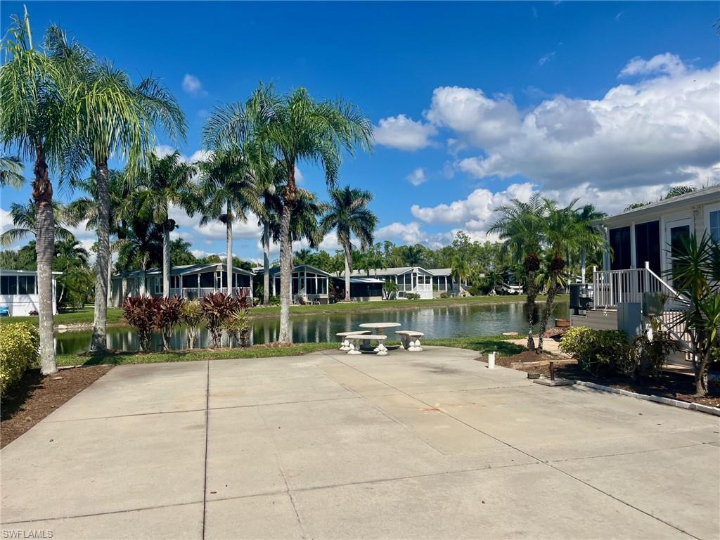 1262 Silver Lakes Boulevard Naples, FL 34114 - Photo 3 of 7 a view of a patio with table and chairs under an umbrella with palm trees