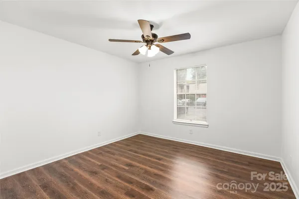 an empty room with wooden floor ceiling fan and windows