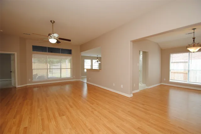 a view of an empty room with window and wooden floor