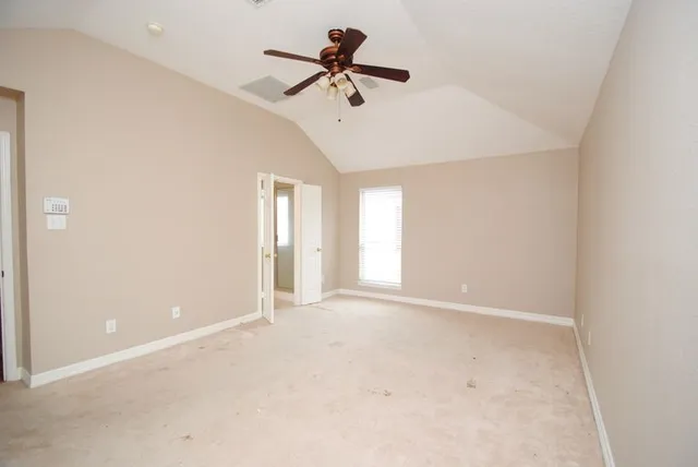 an empty room with ceiling fan and window