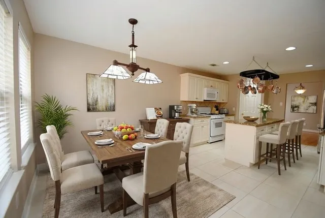 a dining room with wooden floor a chandelier a wooden table and chairs
