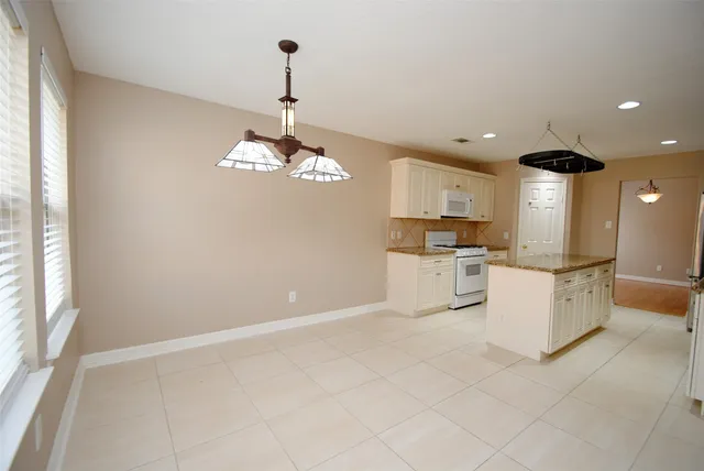 a large kitchen with granite countertop a large counter top a sink stainless steel appliances and cabinets