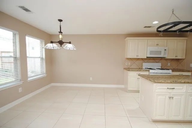 a kitchen with granite countertop white cabinets and window