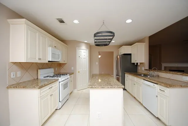 a large kitchen with kitchen island granite countertop a sink stainless steel appliances cabinets and a counter top space