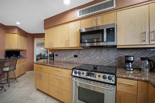 a kitchen with stainless steel appliances granite countertop a refrigerator and a stove top oven