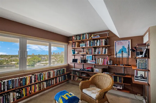 a living room with furniture a bookshelf and a large window