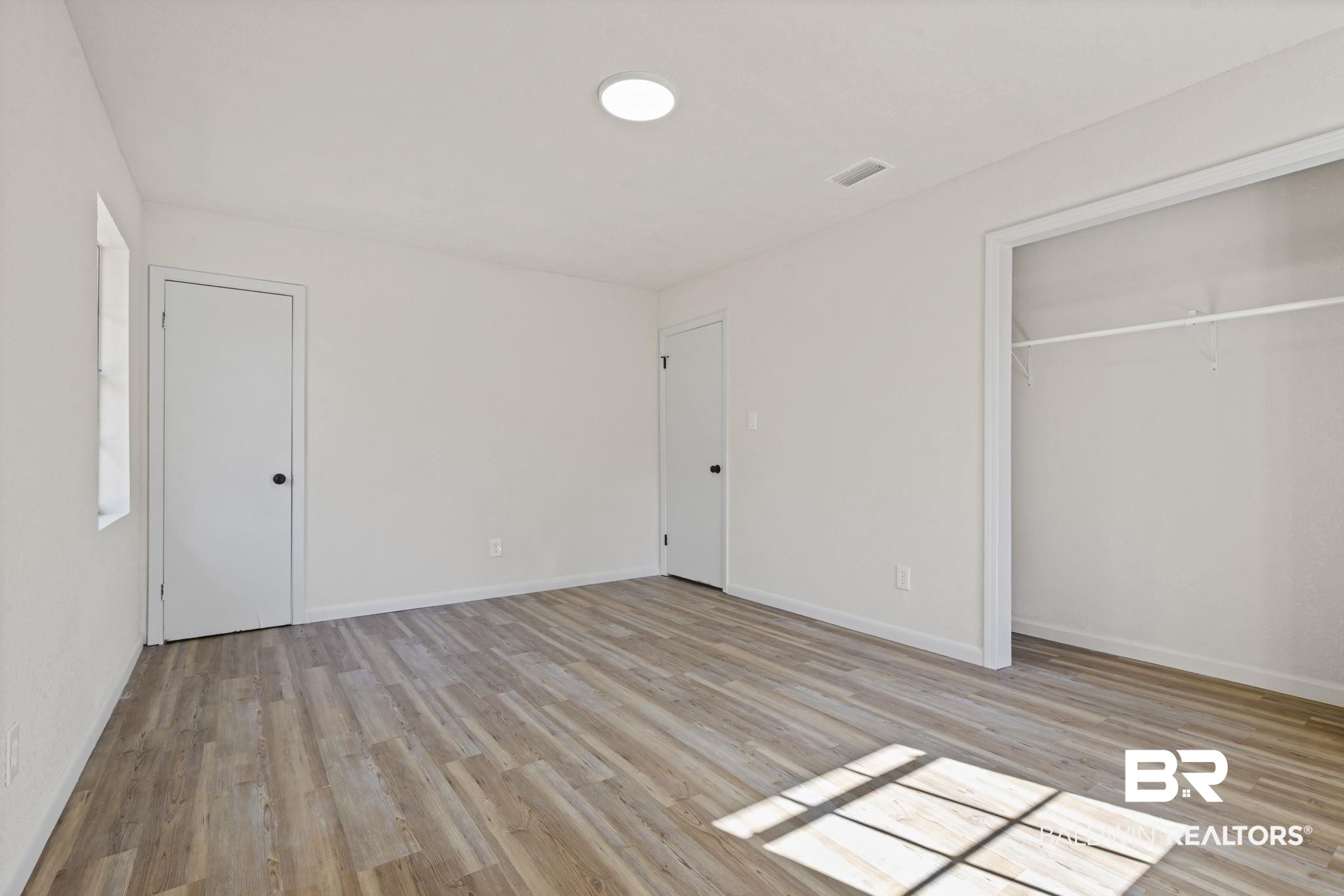 910 Moran Street Bay Minette, AL 36507 - Photo 8 of 20 Unfurnished bedroom featuring light wood-style flooring and a closet