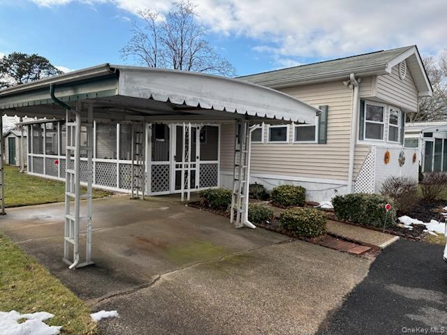 View of front of home featuring concrete driveway and a carport