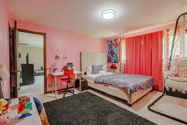 a bedroom with a bed and a lamp on dresser