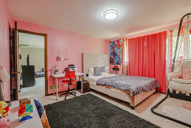 a bedroom with a bed and a lamp on dresser