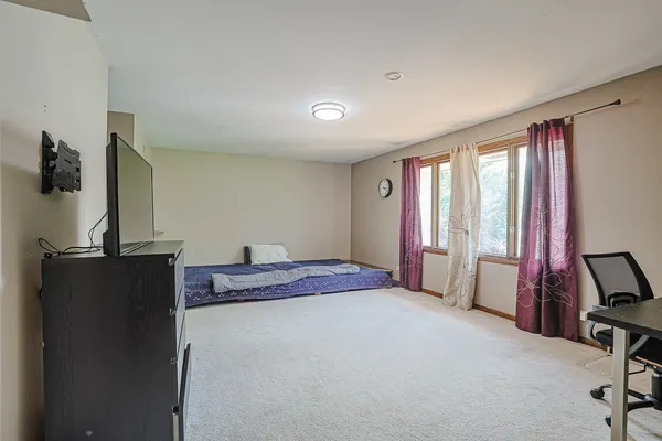 a bedroom with a bed and a flat tv screen on the dresser