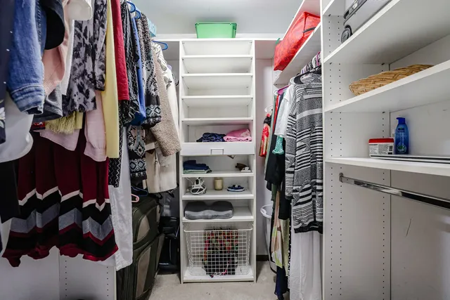 a view of walk in closet with clothes and shoes