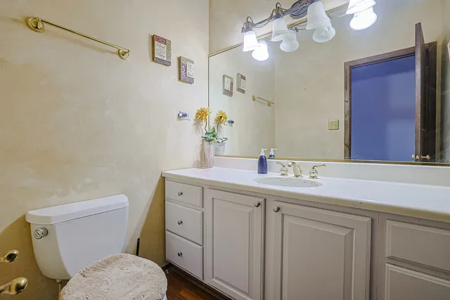 a bathroom with a granite countertop toilet sink and mirror