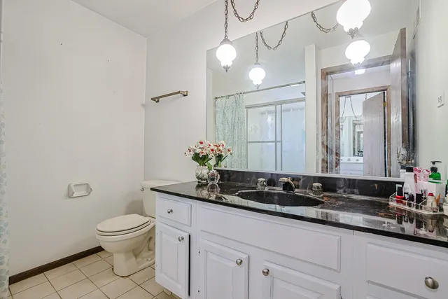 a bathroom with a granite countertop sink a toilet and a mirror