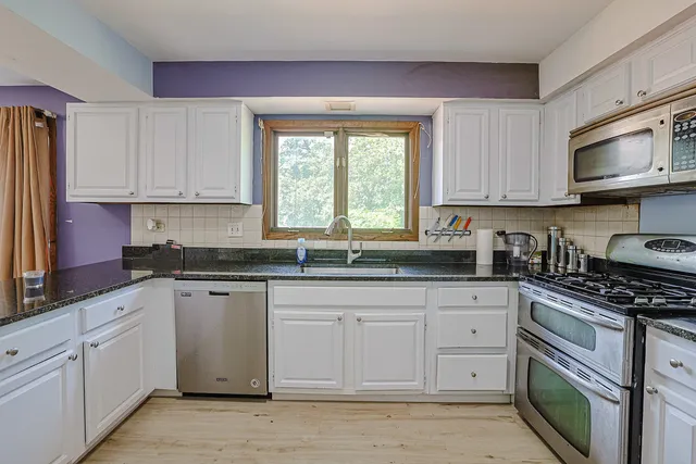 a kitchen with granite countertop a sink a stove and cabinets