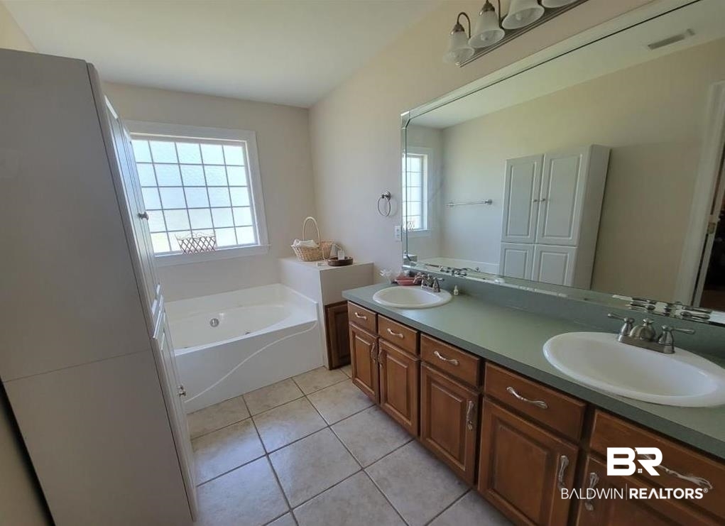 16311 Old Brady Road Bay Minette, AL 36507 - Photo 13 of 38 Bathroom featuring a soaking tub with frosted glass block window, dual vanity with undermount sinks, wood-finish cabinetry, and tiled flooring