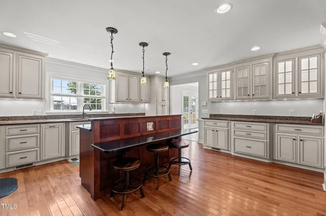 a kitchen with kitchen island granite countertop wooden floors and white cabinets