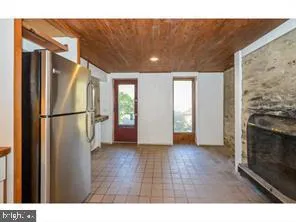 a view of a refrigerator in kitchen and an empty room
