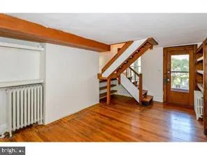 a view of an empty room with wooden floor and stairs