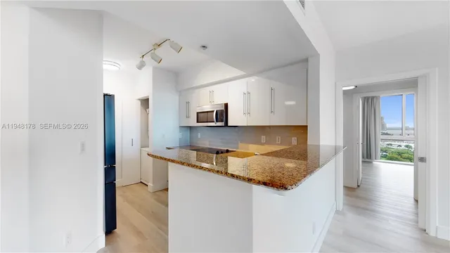 a kitchen with stainless steel appliances granite countertop a sink and a refrigerator