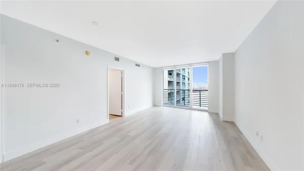 a view of an empty room with wooden floor and a window