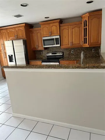 a view of a refrigerator a microwave and cabinets
