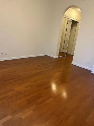 an empty room with wooden floor and mirror