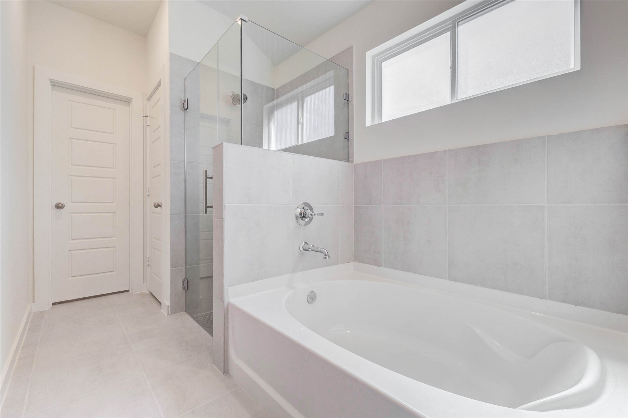 6467 Escondido Drive Rosharon, TX 77583 - Photo 19 of 32 Primary bathroom featuring a soaking tub, separate glass-enclosed shower, neutral tile surround, high privacy window, and clean modern finishes. The layout offers a relaxing bath area with a separate shower zone, creating a comfortable and practical en-suite retreat.