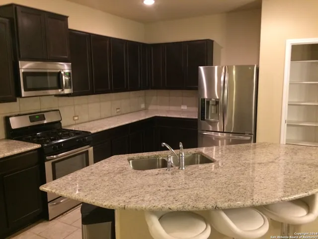 a kitchen with granite countertop a stove and a refrigerator