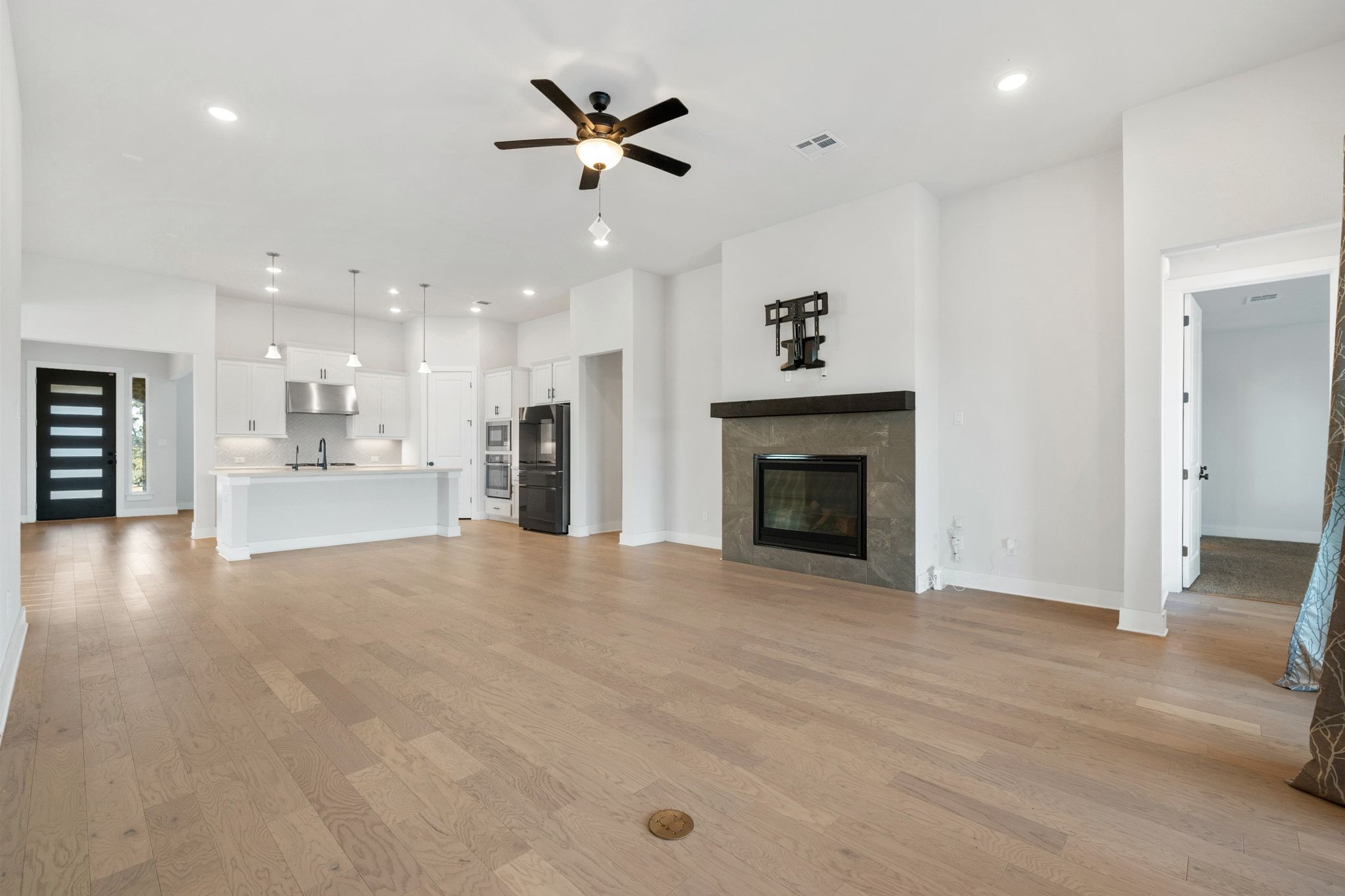 957 Arrowhead Ranch Boulevard Dripping Springs, TX 78620 - Photo 9 of 31 Unfurnished living room with a ceiling fan, a tiled fireplace, light wood-style floors, and recessed lighting
