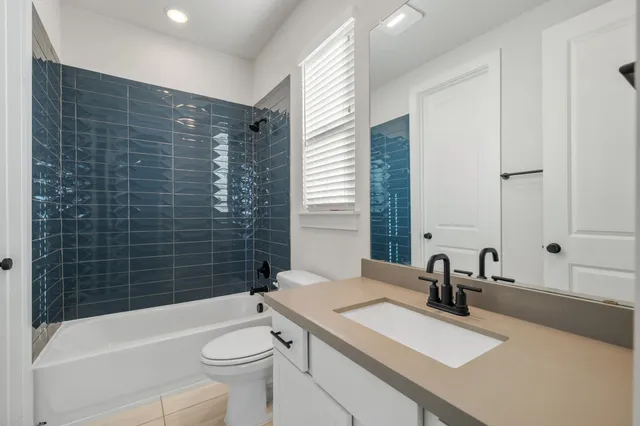 a bathroom with a sink a toilet a mirror a vanity and bathtub