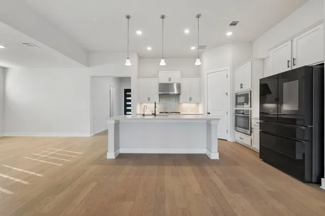 a large kitchen with stainless steel appliances a sink and a large window