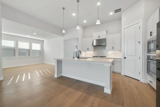 a large white kitchen with a refrigerator a stove a sink and a large window