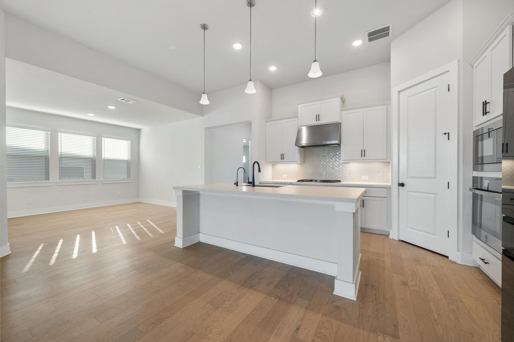 957 Arrowhead Ranch Boulevard Dripping Springs, TX 78620 - Photo 6 of 31 Kitchen with white cabinetry, hanging light fixtures, light wood-type flooring, recessed lighting, and a center island with sink