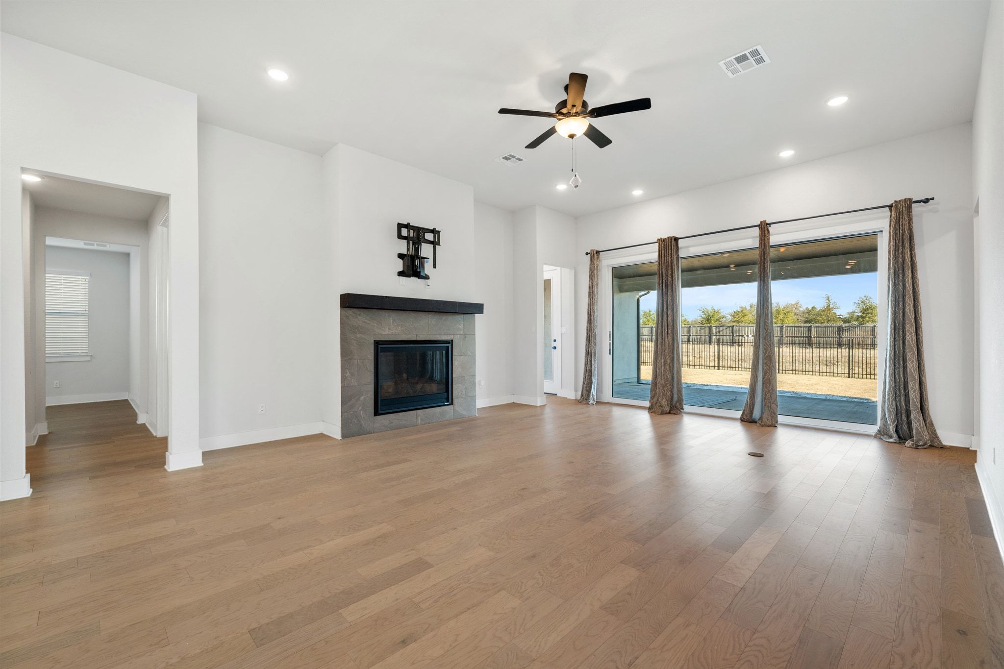 957 Arrowhead Ranch Boulevard Dripping Springs, TX 78620 - Photo 8 of 31 Unfurnished living room featuring ceiling fan, a fireplace, light wood-style floors, and recessed lighting